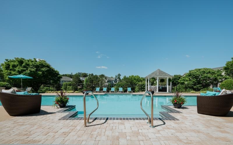 a pool with a deck and chairs by it and trees in the back